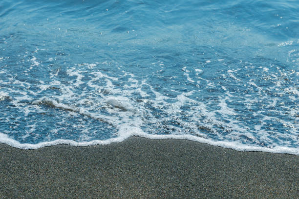 istock White foam wave on the black sand beach close-up 1306585063