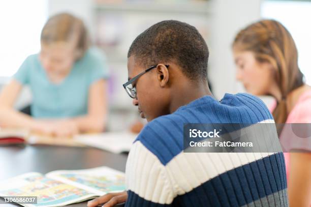 African Teenage Boy Reading A Book At The Library Stock Photo - Download Image Now - Teenager, High School Student, Adolescence