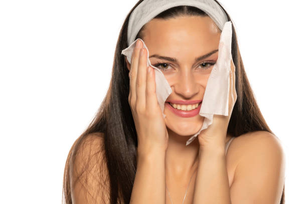 istock young smiling woman cleaning her face with wet tissues 1306586153