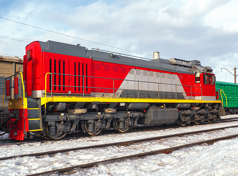 Switcher with train of freight cars in line at a rail yard. Small diesel maneuvering locomotive.