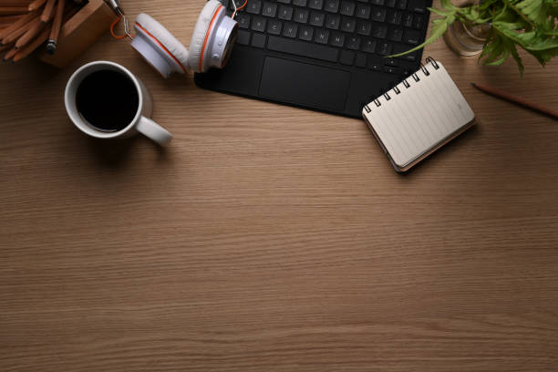 istock Top view of office desk with coffee cup, keyboard, headphone, plant, notebook and copy space on wooden background. 1306595891