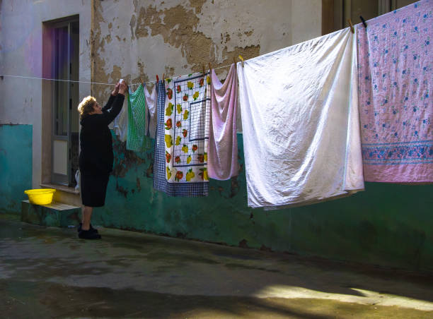 Ragusa, Sicily: A senior woman hanging colorful sheets outside in Ragusa, a UNESCO World Heritage Site in the Val di Noto.