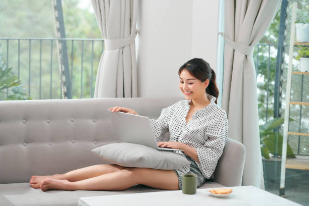 istock A asian woman spending time at home, sitting on sofa, using her laptop 1306604601