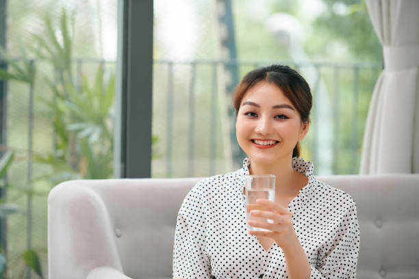 istock Beautiful young woman drinking water at home 1306604805