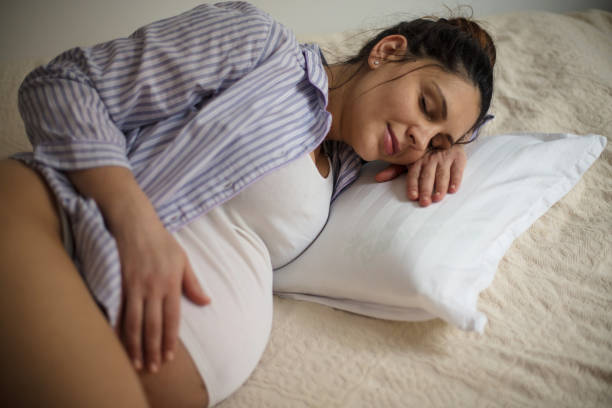 istock Pregnant woman sleeping on bed and touching her belly. 1306616621