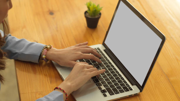 istock Female hands typing on laptop keyboard with mock up screen on wooden table 1306619772