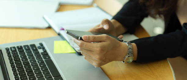 istock Businesswoman using smartphone while working with office supplies on office desk 1306619810