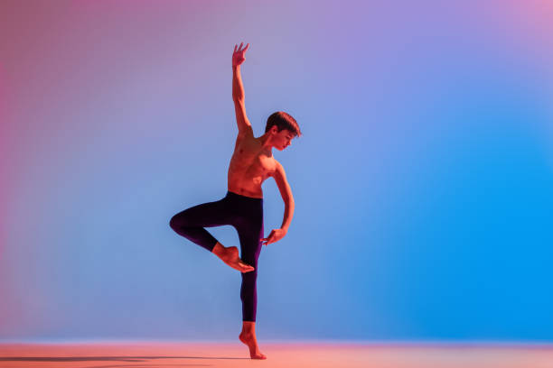 istock teenage ballet boy dancer dances barefoot under a colored light. 1306620906
