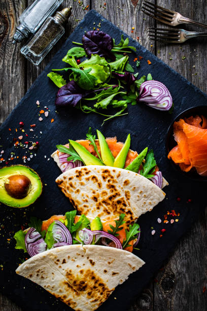 istock Italian piada wraps - piada stuffed with smoked salmon, avocado, arugula and onion on black stone plate 1306626076