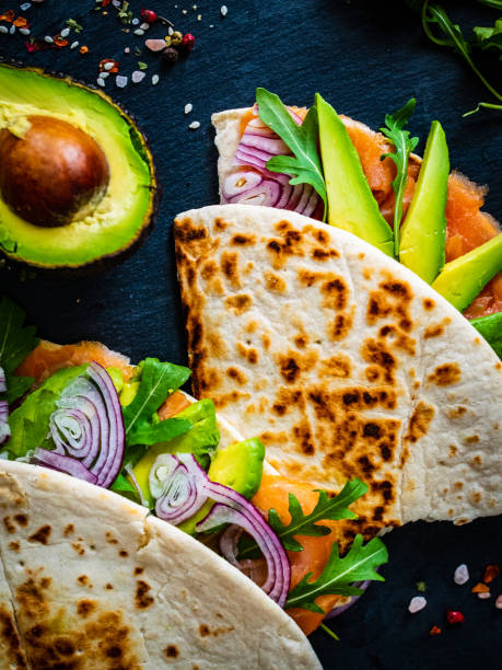 istock Italian piada wraps - piada stuffed with smoked salmon, avocado, arugula and onion on black stone plate 1306626376