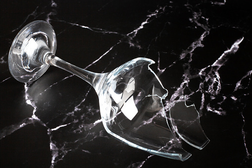Broken shattered wine glass and shard on marble background close up