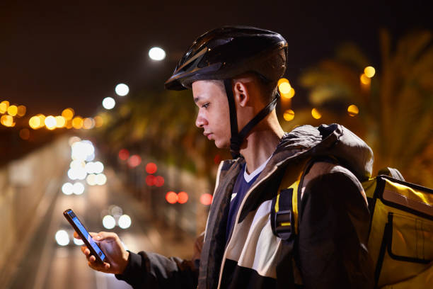 istock Delivery biker at dusk looking at the phone's screen. 1306631049