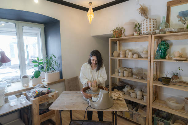istock Female ceramist working on pottery wheel  in her studio 1306631197