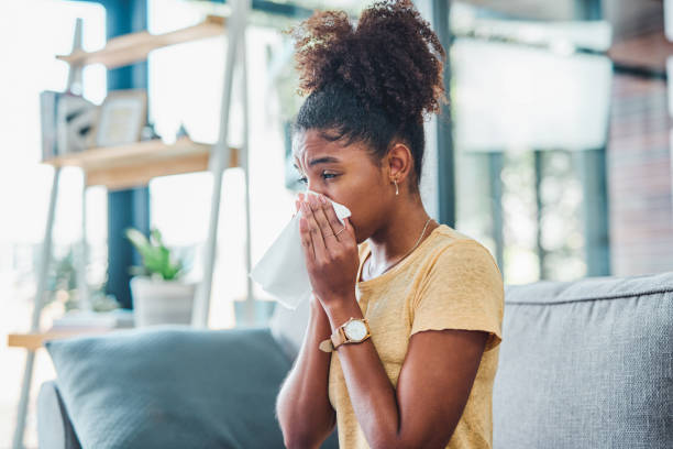 A day of rest is the route to recovery Shot of a young woman feeling ill on the sofa at home sneezing stock pictures, royalty-free photos & images