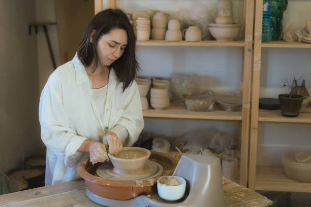 istock Female ceramist working on pottery wheel  in her studio 1306634979