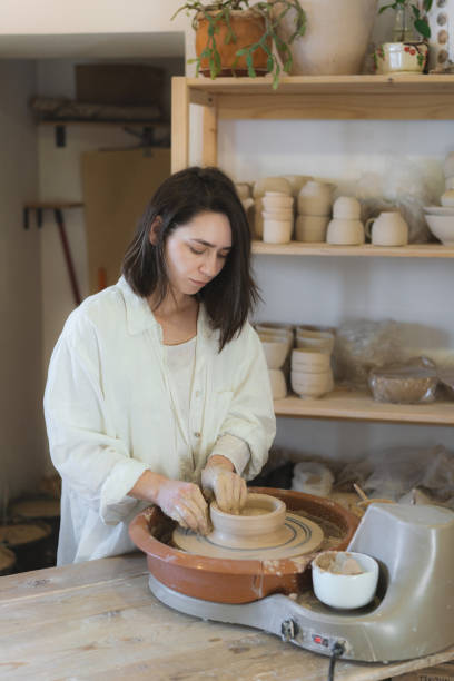 istock Female ceramist working on pottery wheel  in her studio 1306634986