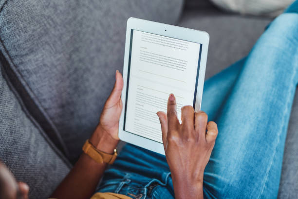 The digital magazine that's so worth the download Shot of an unrecognisable woman using a digital tablet on the sofa at home e reader stock pictures, royalty-free photos & images