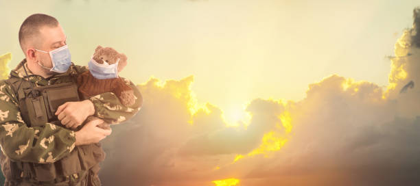istock Soldier with teddy-bear  on sunrise background . 1306639215
