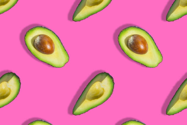 istock Seamless pattern of fresh ripe green avocado fruit half isolated on pink background. Top view. Banner. Flat lay composition. Pop art design. Creative summer food background 1306639563