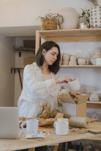 彼女のスタジオでの女性のセラミスト梱包注文 - potter small business pottery happiness ストックフォトと画像