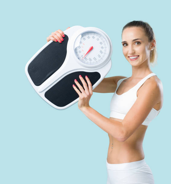 istock Smiling slim woman holding a weight scale 1306644521