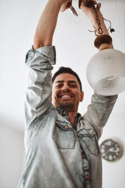 hombre sonriente reparando luz de techo en casa - led lighting equipment light bulb installing fotografías e imágenes de stock