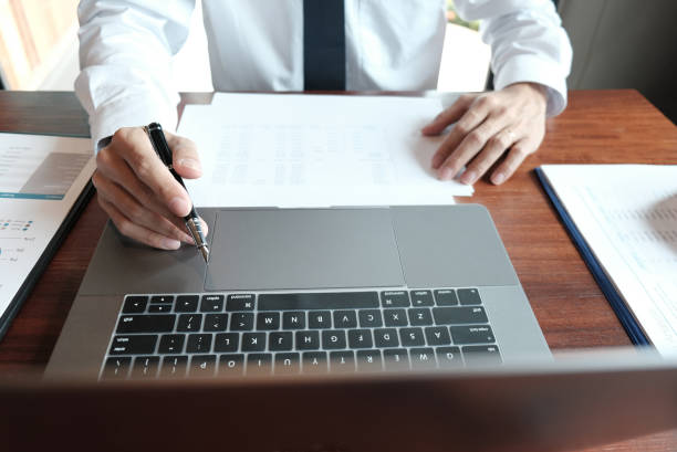 istock Businessman analyzing investment charts and pressing calculator buttons over documents. Accounting Concept. 1306646950