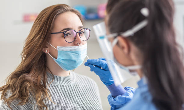 le masque féminin de port de patient au-dessus de la bouche est ayant l’échantillon pris du nez pour un essai de pcr pour covid 19. - test médical photos et images de collection