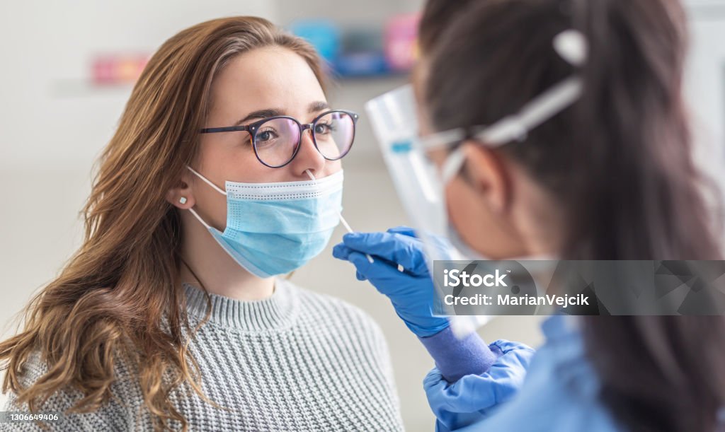 Female patient wearing mask over mouth is having sample taken from nose for a pcr test for Covid 19. Coronavirus Stock Photo