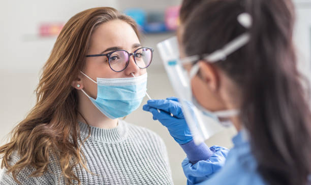 Female patient wearing mask over mouth is having sample taken from nose for a pcr test for Covid 19. Female patient wearing mask over mouth is having sample taken from nose for a pcr test for Covid 19. pcr device stock pictures, royalty-free photos & images
