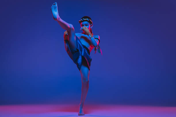 istock Young boy thai boxer training over blue background in neon light. 1306649646