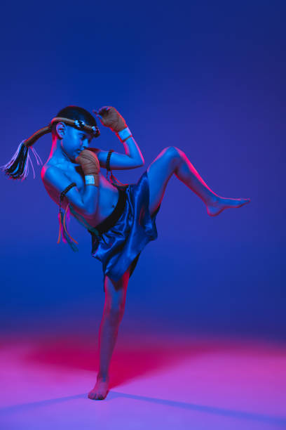 istock Young boy thai boxer training over blue background in neon light. 1306650111