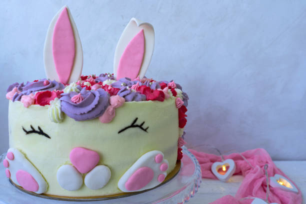istock Cheerful bunny cake for Easter and Birthday. Greeting card. Modern concept design. Tall cake with a funny face and ears. 1306651938