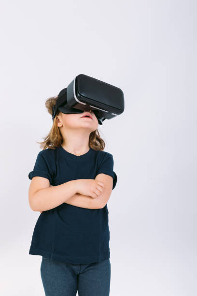 istock Little girl with virtual reality glasses looking up on white background 1306654149