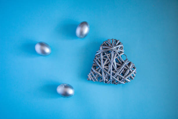 Silver eggs and a decorative silver heart on a delicate blue background. concept of rich Easter holidays, greeting cards and spring love.