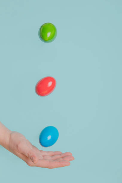 istock Hand catching flying coloured eggs, easter minimal concept blue pastel background. Flothing eggs 1306655394