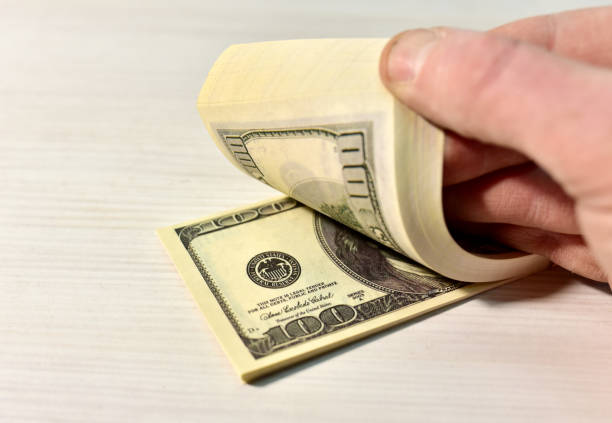 istock A bundle of one hundred dollar bills during counting. Money account concept. Man's hand counts dollars. 1306655817