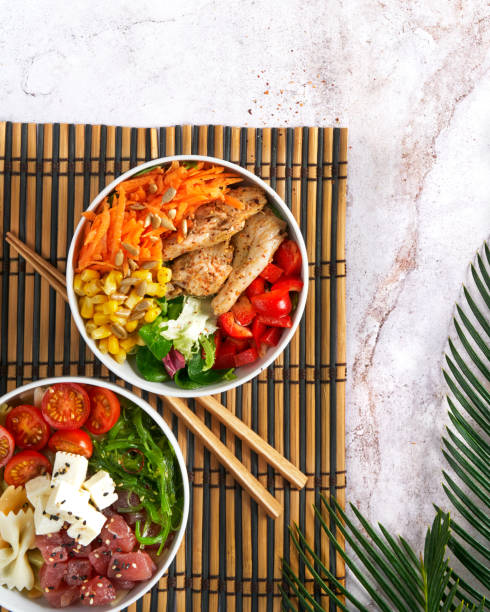 Hawaiian trendy poke bowls, tuna, heura soy protein or vegan chicken, variety vegetables, served in bowl on tropical leaves. Marble table, Top view. Copy space. Fast healthy lunch, nutrition concept. cuencos de poke de moda hawaianos, atún, proteína de soja heura o pollo vegano, vegetales de variedad, servidos en tazón en hojas tropicales. mesa de mármol, vista superior. almuerzo rápido y saludable, concepto de nutrición. copiar espacio.