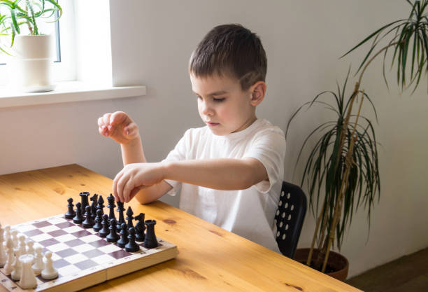 istock A preschool boy arranges pieces on a chessboard for playing chess. Board games. 1306661514