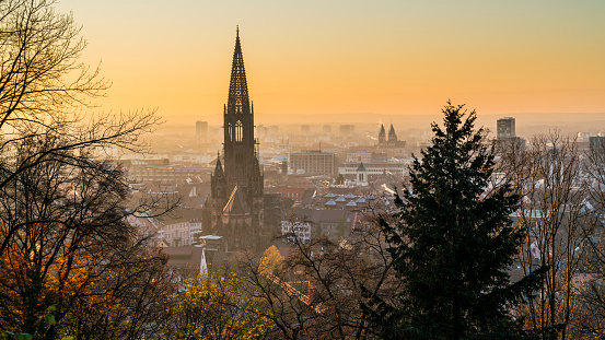 Germany, Freiburg im Breisgau, Magical orange sunset sky above skyline of the beautiful city and muenster on cold winter day