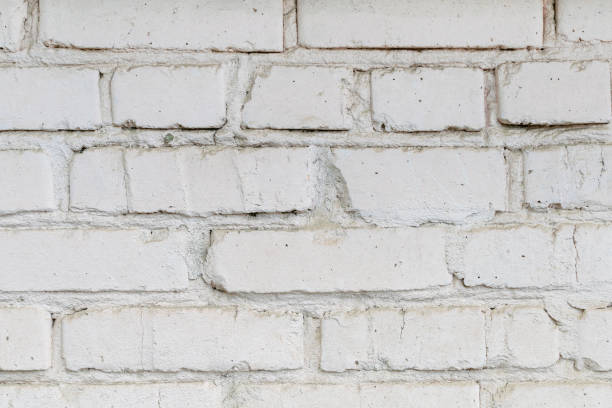 istock Old dirty painted white brick wall background, grungy texture. Building facade outside close-up 1306662086