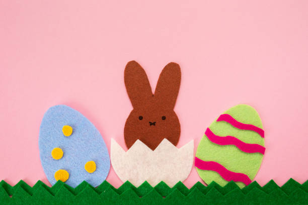 istock Easter decorations. Cut out the felt applications of two colorful eggs and brown rabbit hatched from the egg. Pink background. Flat lay. Copy space. Holiday concept 1306666224