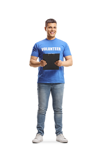 Full length portrait of a young man volunteer holding a clipboard isolated on white background