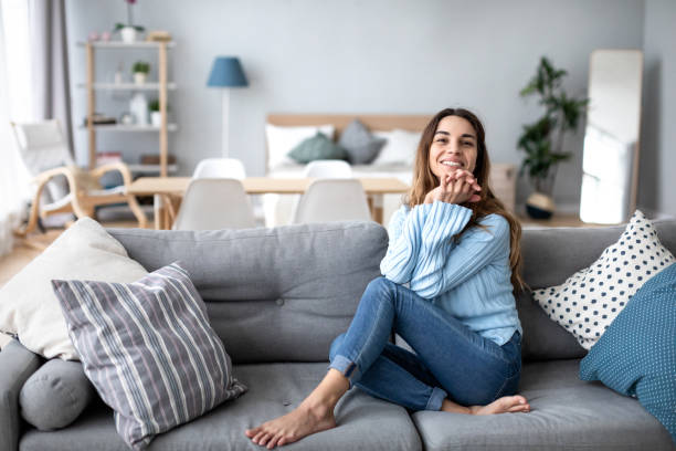 istock Relaxed smiling woman sitting on sofa alone at home. 1306668952