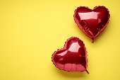 Red heart shaped balloons on yellow background, flat lay with space for text. Valentine's Day celebration