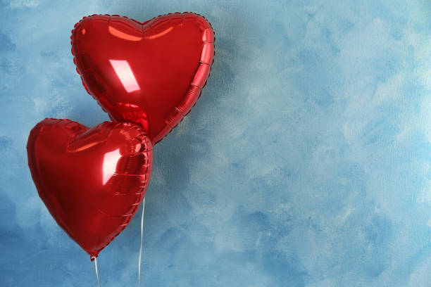 istock Red heart shaped balloons near light blue wall, space for text. Valentine's Day celebration 1306670199