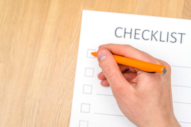 istock A man's hand holds a pen and writes a check list with checkboxes, a wooden table. Time management concept 1306670680