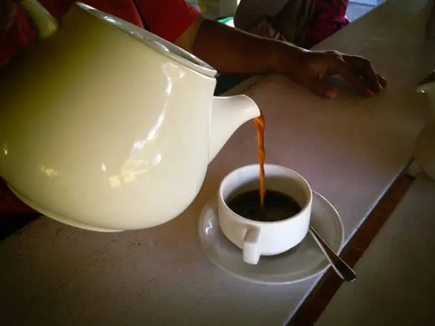 Pouring A Cup Of Coffee From Glass Coffee Pot On A Wooden Table