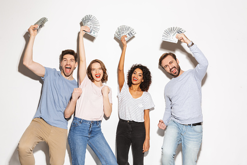 Group of happy multiracial people holding money banknotes and celebrating isolated over white background
