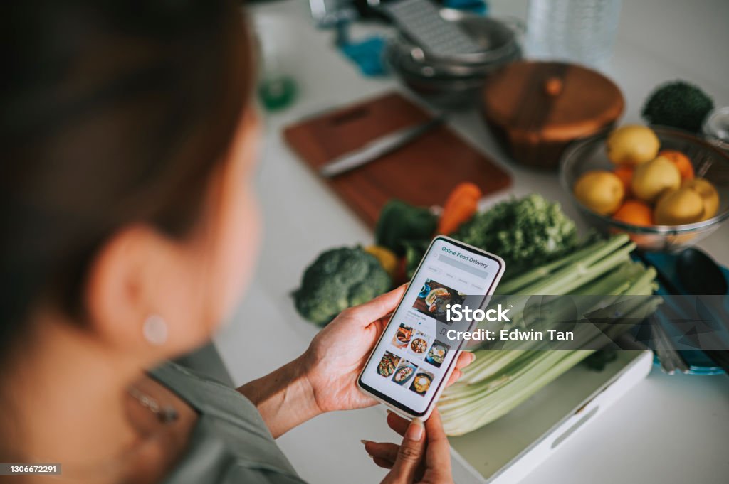 High angle view asian chinese woman's hand on mobile app for online food delivery in front of kitchen counter Healthy Eating Stock Photo